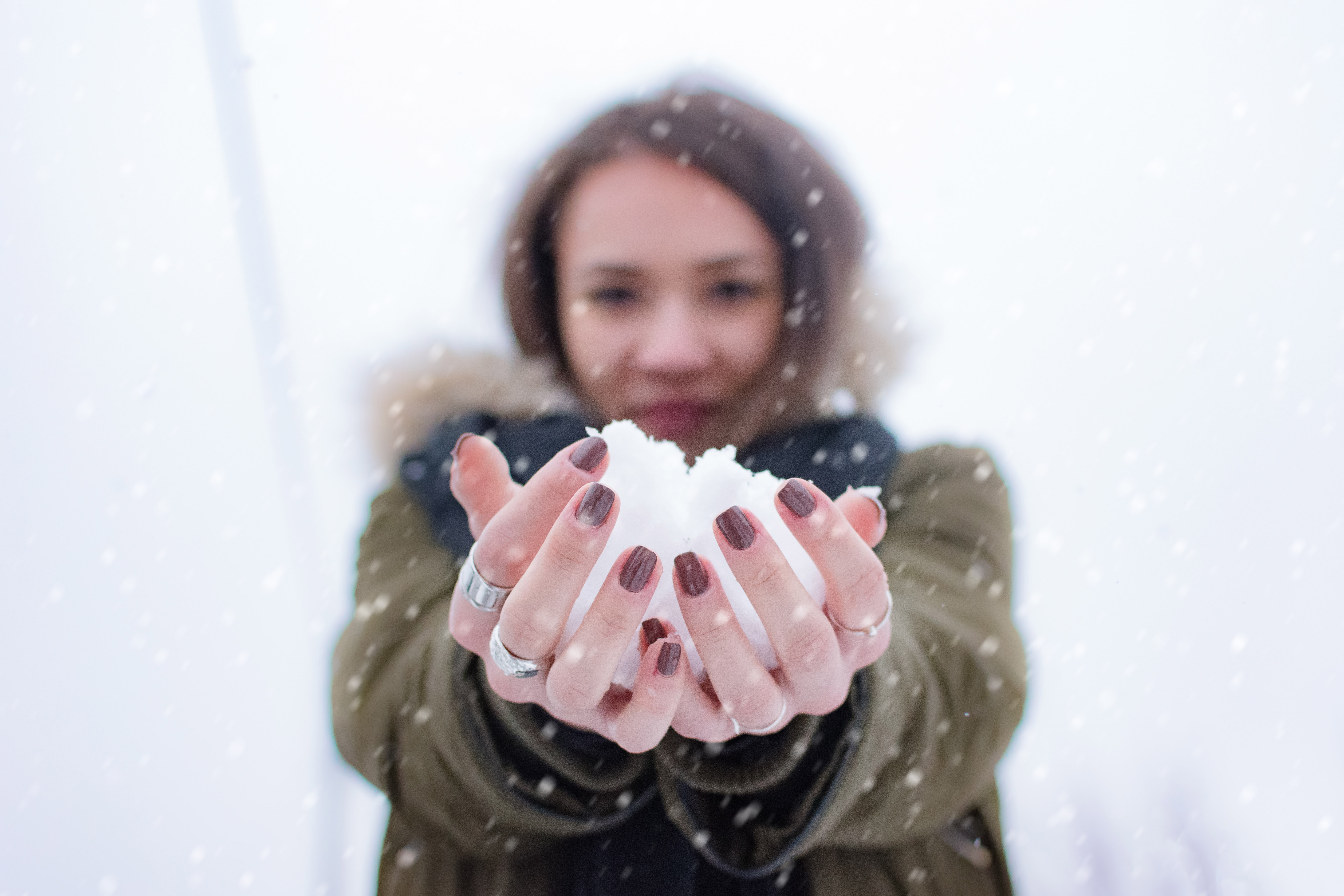 Woman with outstretched arms holding snow in her hands