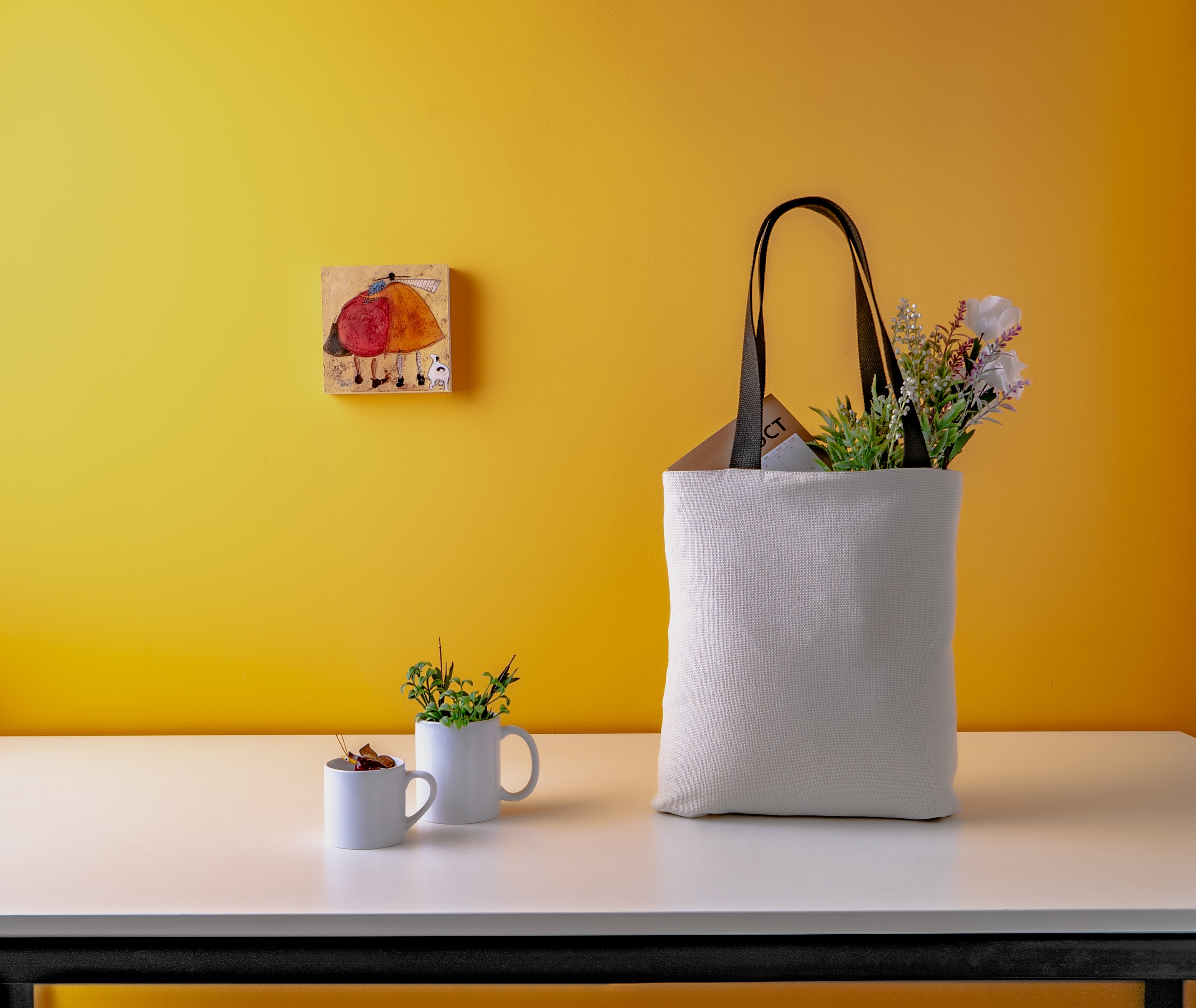 two white ceramic mugs and a white bag on wooden table